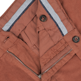 Close-up of the Muted Orange Cotton Corduroy High Comfort Chinos by Incotex highlighting the waistband, button closures, and an open metal zipper.