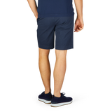 Man wearing Incotex navy blue cotton high comfort shorts and sneakers standing sideways.