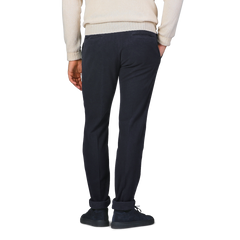 A person in a white sweater and Incotex Navy Blue Cotton Moleskin Model 30 Chinos stands facing away, with hands relaxed by their sides.