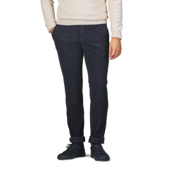 A person wearing a cream sweater, Incotex Navy Blue Cotton Moleskin Model 30 Chinos, and black sneakers stands with hands in pockets.