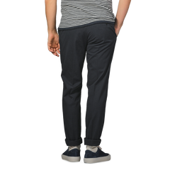 An individual in a striped shirt and Incotex's Navy Blue Cotton Royal Batavia Regular Chinos stands with hands in pockets, facing away.