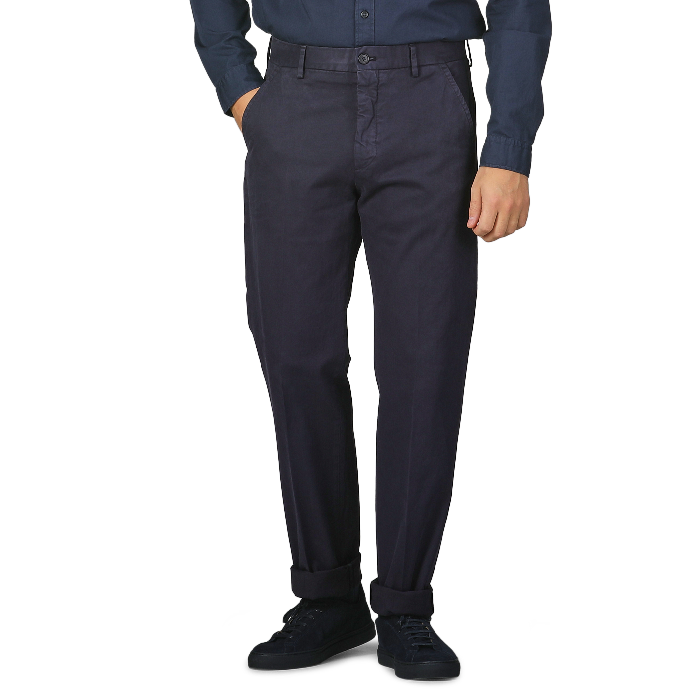 A person stands against a plain background, hands in pockets, dressed in a dark blue shirt paired with Incotex's Navy Blue Cotton Stretch Model 8 Chinos.