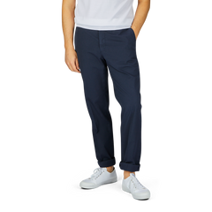 A person wearing a white t-shirt, Navy Blue Cotton Stretch Regular Chinos by Incotex, and white sneakers stands with one hand in their pocket against a plain background.