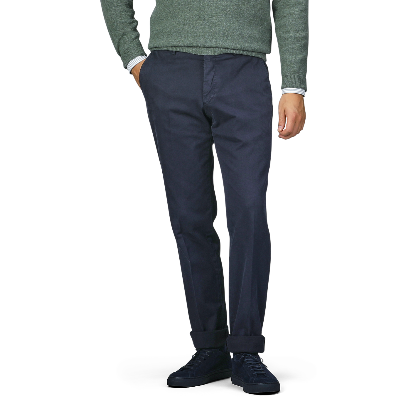 A person wearing Incotex's navy blue cotton twill regular chinos, a green sweater, and black shoes stands with one hand in their pocket.