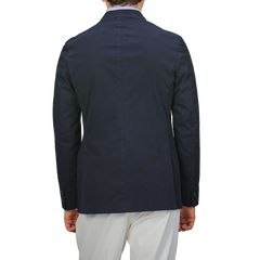 Rear view of a person wearing the Incotex Navy Blue Washed Cotton Batavia Blazer with white pants, highlighting its unstructured design against a plain background.