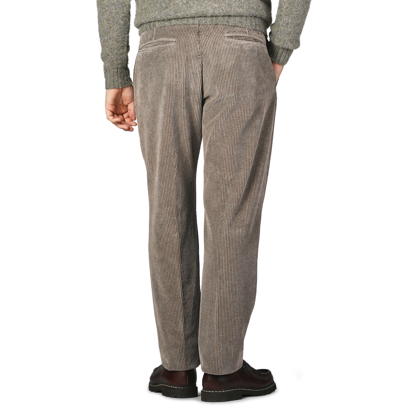 A person stands facing away, wearing Incotex stone grey cotton corduroy regular fit trousers paired with a grey sweater and dark shoes.