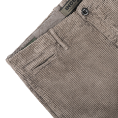 Close-up of the stone grey cotton corduroy trousers by Incotex, highlighting the waistband, a front pocket, and a button marked with "INCOTEX.