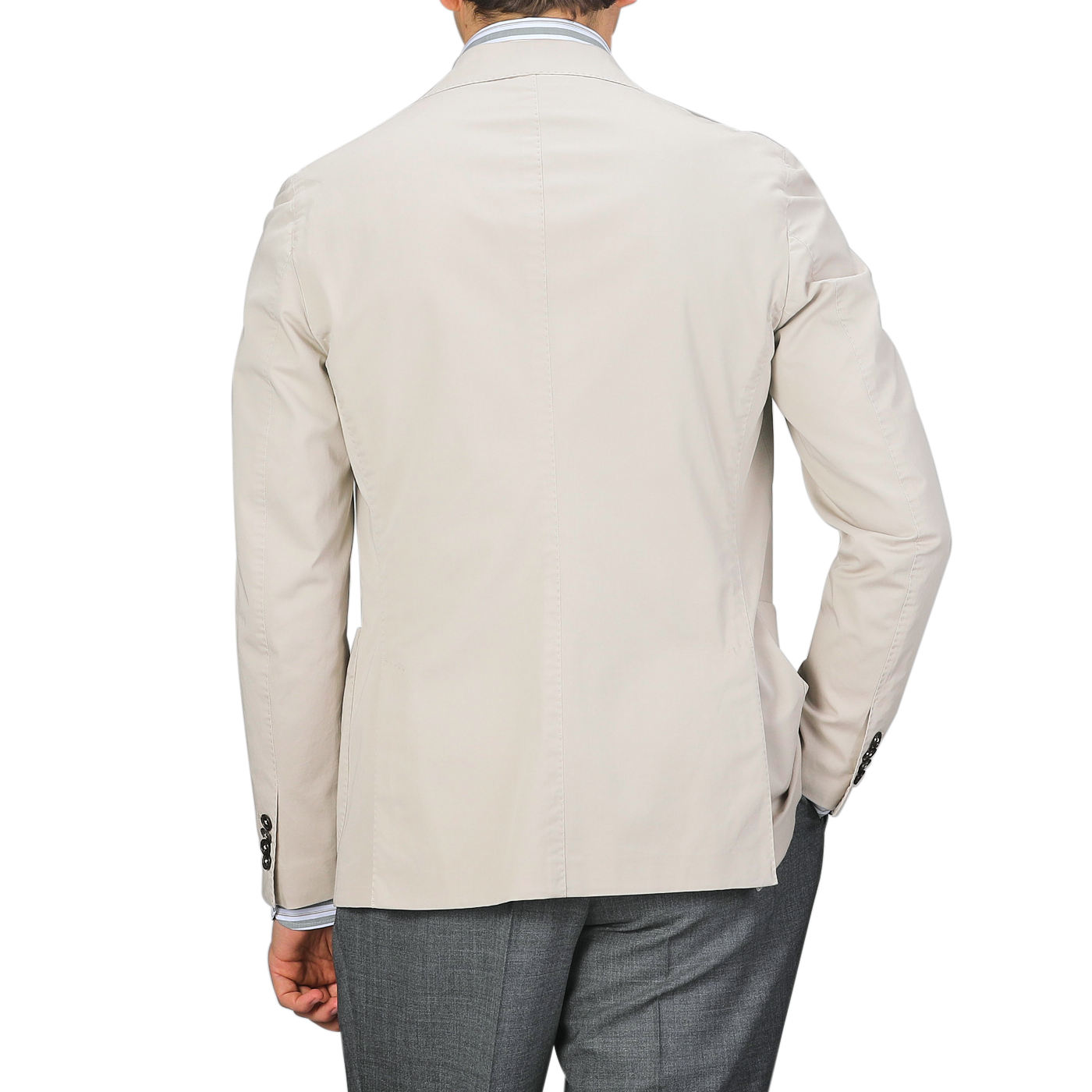 An individual wearing an Incotex Taupe Beige Washed Cotton Batavia Blazer in slim fit and gray pants is seen with their back turned against a neutral background.