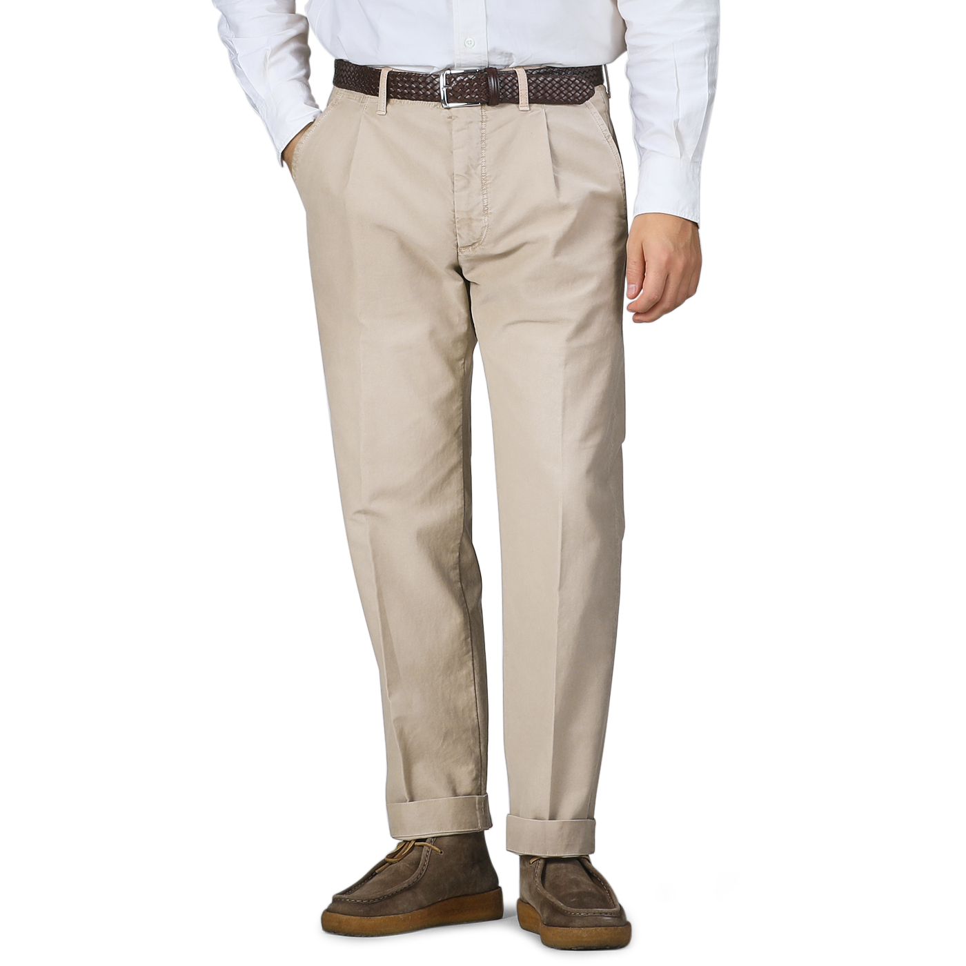 A person wearing Incotex Washed Beige Single Pleat Cotton Slacks, a white shirt, a brown belt, and brown shoes stands with hands in pockets.