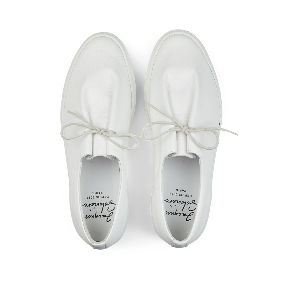 A pair of contemporary Jacques Soloviére Paris Jim sneakers crafted from white grained leather, featuring slip-on design with laces, displayed against a white background.