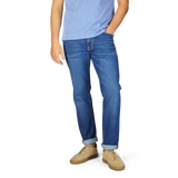 Man wearing Jeanerica Medium Blue Washed Cotton TM005 jeans and light blue t-shirt with tan shoes, standing with his left hand in pocket.