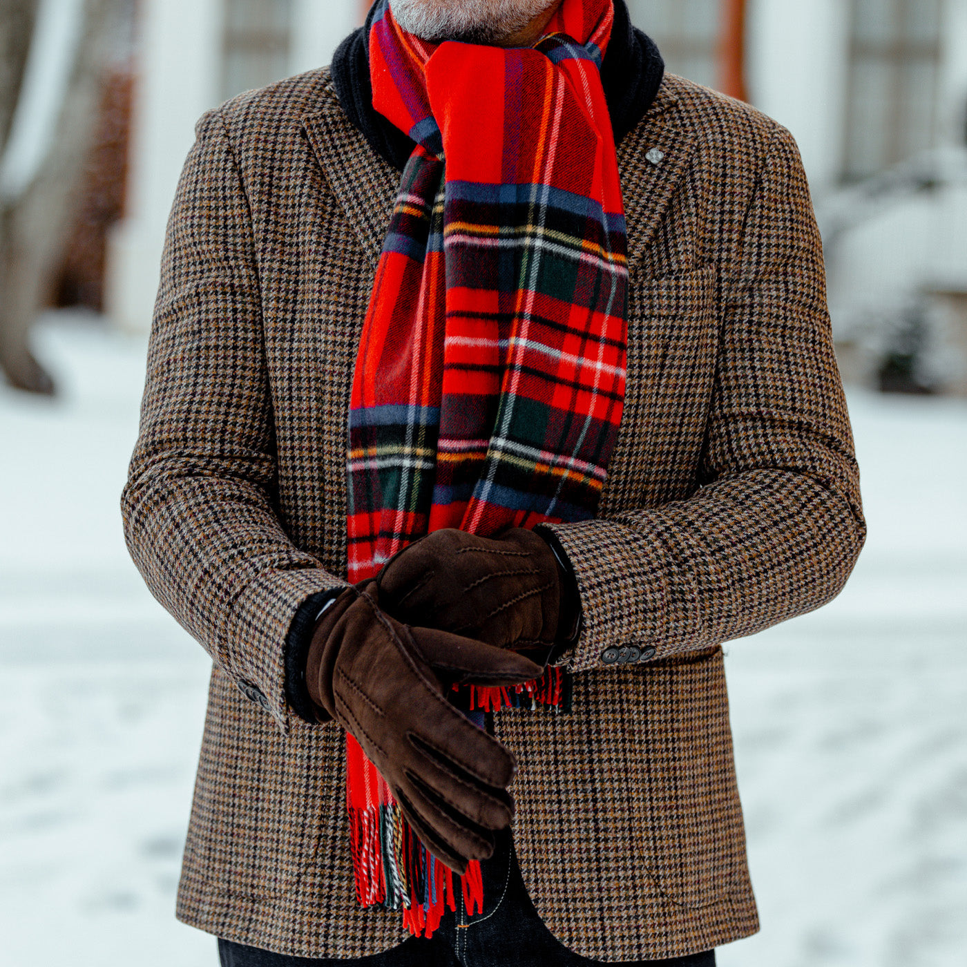 A man wearing a Red Checked Royal Stewart Cashmere Scarf by Johnstons of Elgin.