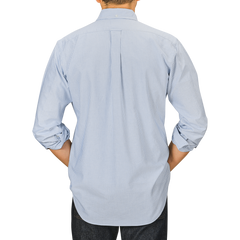 Person wearing a light blue, long-sleeved Kamakura Shirts' Blue Striped Washed Cotton Oxford BD Shirt, seen from the back facing a neutral background.