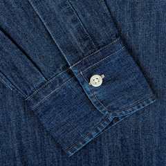 Close-up of a dark blue Japanese denim 7oz BD shirt sleeve with a buttoned cuff from Kamakura Shirts. The pure cotton fabric showcases a visible weave and stitching.