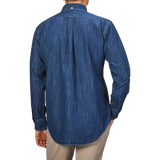 A person stands facing away, wearing a Kamakura Shirts Dark Blue Japanese Denim 7oz BD Shirt with a button-down collar and beige pants.