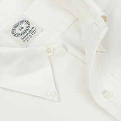 Close-up of the Ecru Washed Cotton Oxford BD Shirt by Kamakura Shirts from the Vintage Ivy collection, showcasing a white button-down design with three visible buttons and labels indicating "All Japan Fabrics," "100% Cotton," and "Made in Japan.