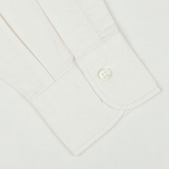 Close-up of the cuff from an Ecru Washed Cotton Oxford BD Shirt by Kamakura Shirts. The casual shirt from the Vintage Ivy collection features a single white button fastened on its subtly textured pure cotton oxford fabric.