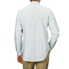 A person wearing a long-sleeved, green striped shirt from the Kamakura Shirts collection with tan pants, seen from the back. The washed cotton oxford fabric and button-down collar add a touch of classic elegance to the ensemble.