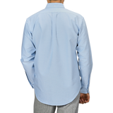 A man is seen from the back wearing a light blue Kamakura Shirts' Washed Cotton Oxford BD Shirt paired with grey trousers, set against a plain background.