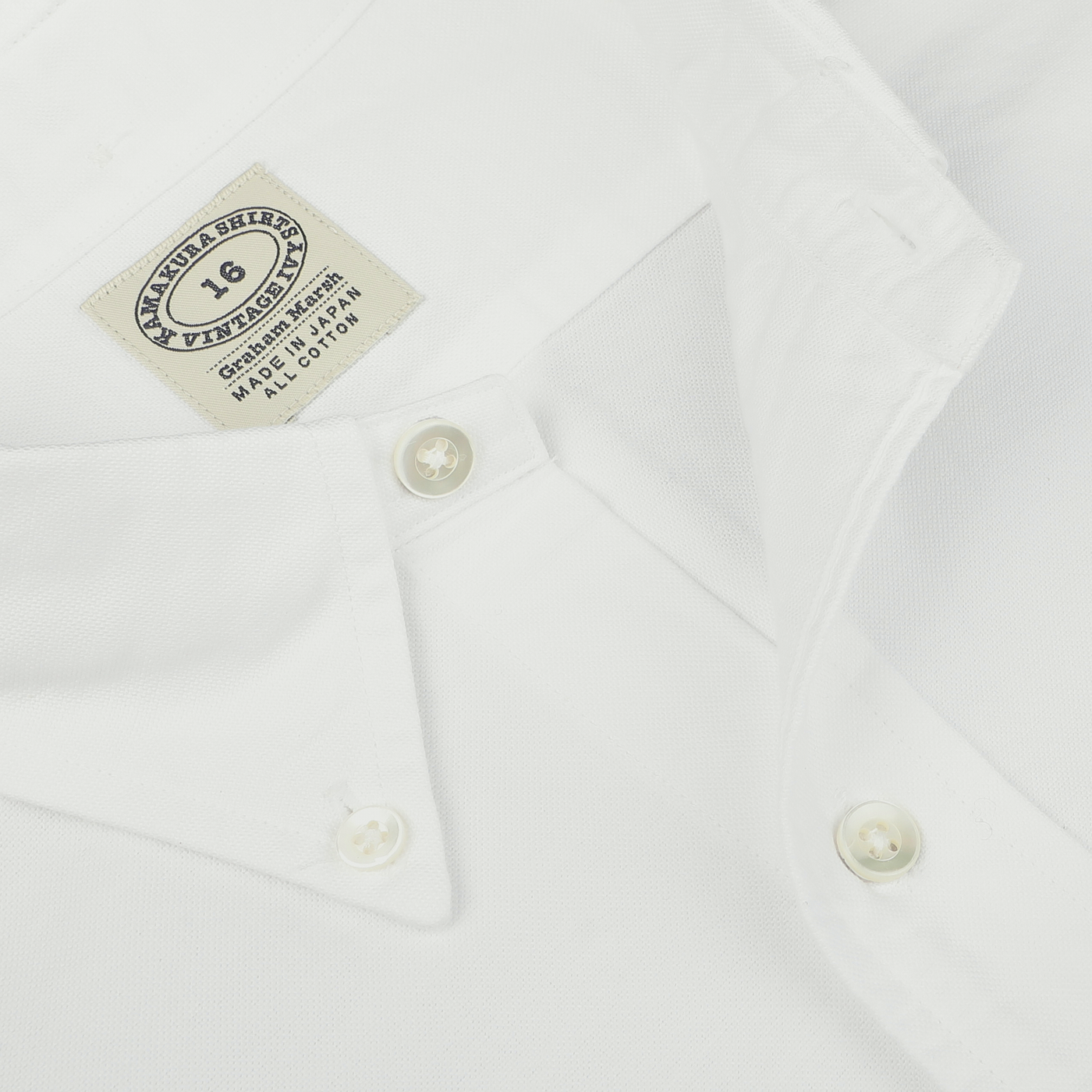 Close-up of a White Washed Cotton Oxford BD Shirt from Kamakura Shirts with a visible label indicating size 16, imported fabric, and made in Korea. The pure cotton oxford shirt exudes timeless elegance and quality craftsmanship.