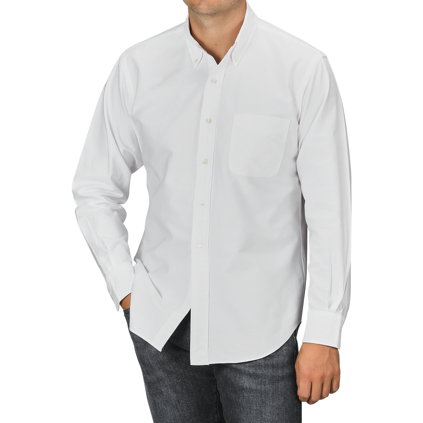 A person is wearing a White Washed Cotton Oxford BD Shirt from Kamakura Shirts, featuring a long-sleeve button-up design with a chest pocket, paired with dark jeans and their left hand in the pocket.