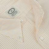 Close-up of a yellow and white striped casual shirt with white buttons from the Kamakura Shirts Vintage Ivy collection. The Yellow Striped Washed Cotton Oxford BD Shirt is made of pure cotton oxford and features a label indicating size 18, made in Vietnam.