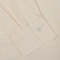 Close-up of a long-sleeve shirt cuff with orange and white vertical stripes, featuring a single button. Part of the Kamakura Shirts Vintage Ivy collection, this casual Yellow Striped Washed Cotton Oxford BD Shirt is crafted from pure cotton oxford.