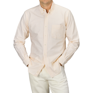 A person wearing a Yellow Striped Washed Cotton Oxford BD Shirt from Kamakura Shirts, paired with white pants, standing with hands in pockets.