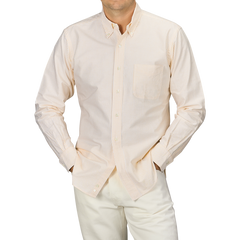 A person wearing a Yellow Striped Washed Cotton Oxford BD Shirt from Kamakura Shirts, paired with white pants, standing with hands in pockets.