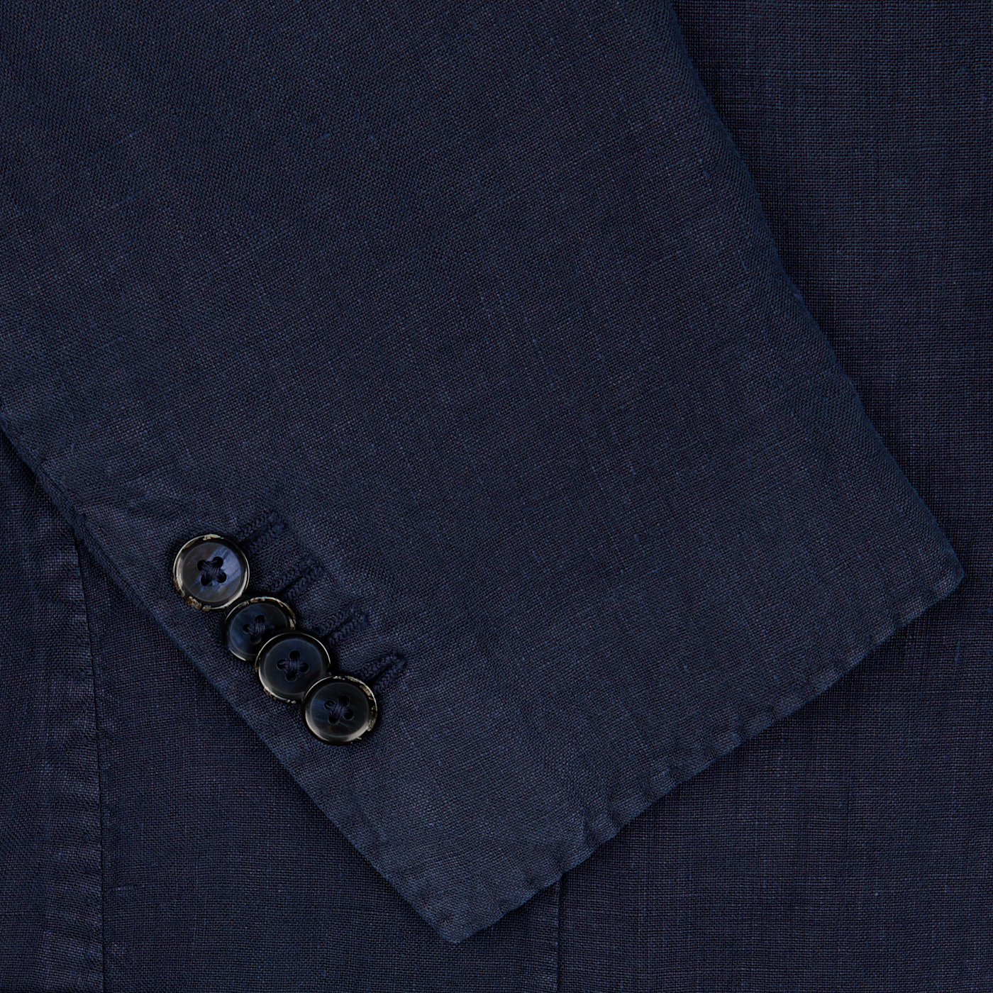 Close-up of a L.B.M. 1911 navy blue washed linen suit sleeve showing detailed texture of the fabric and three glossy black buttons.