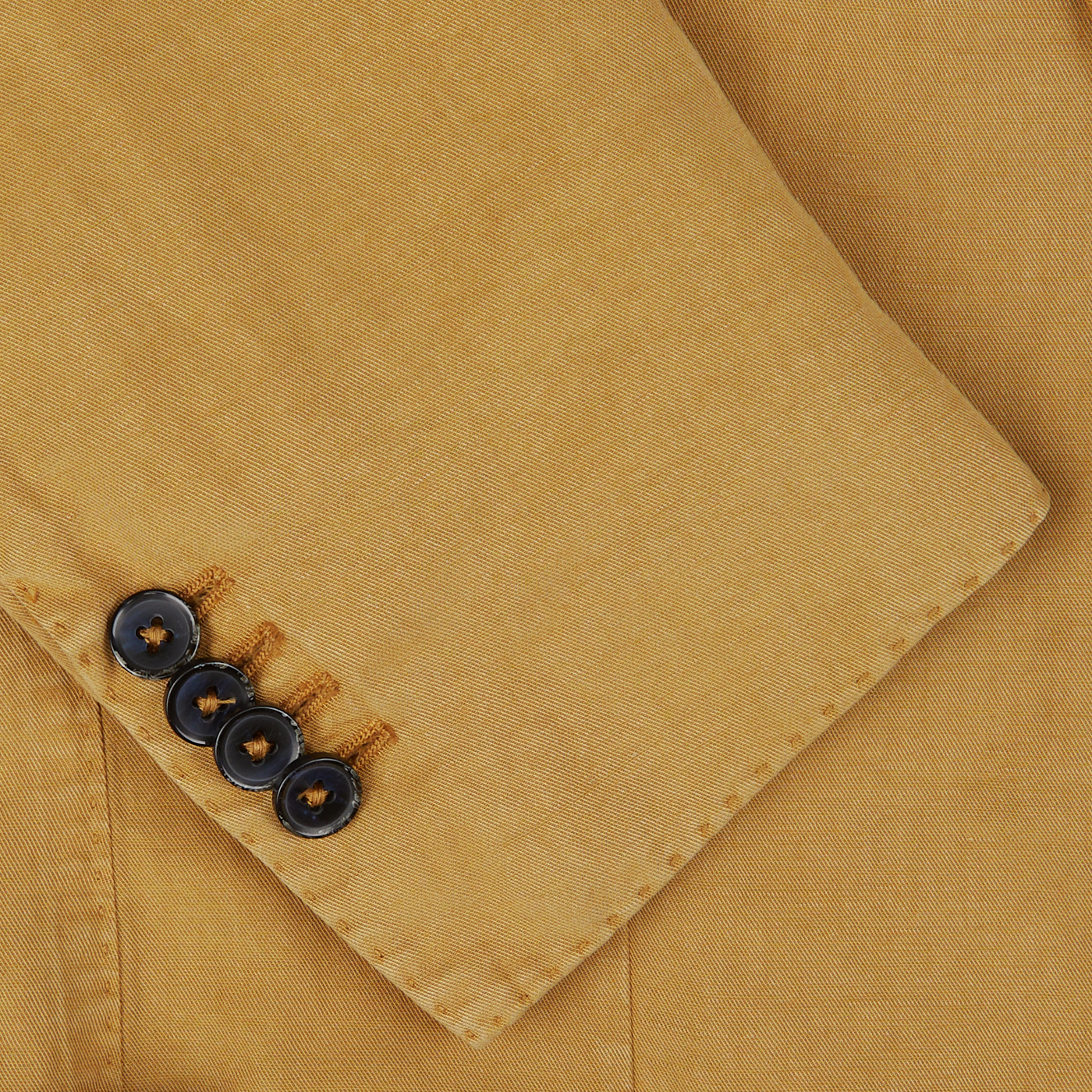 A close-up view of a yellow cotton-linen L.B.M. 1911 blazer sleeve with four black buttons.