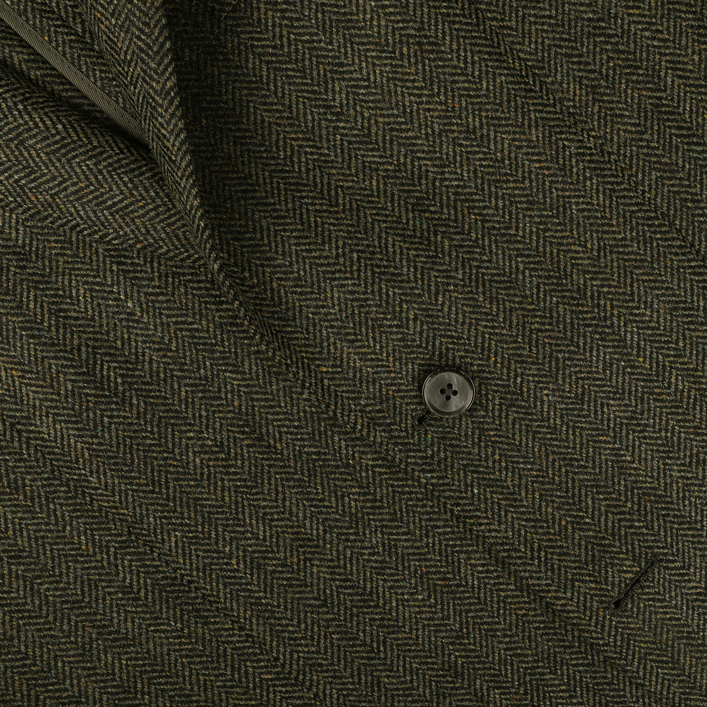 Close-up image of an olive-green and brown herringbone-patterned fabric from the Dark Green Wool Cashmere Herringbone Blazer by L.B.M. 1911, showcasing pure virgin wool with a single black button and a partial view of a pocket.