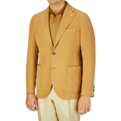 A man wearing a L.B.M. 1911 Dark Beige Washed Cotton Linen Blazer with a lapel pin over a light-colored shirt, paired with cream pants.