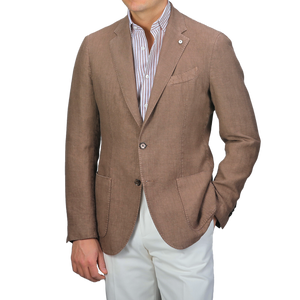 Wearing a slim fit Light Brown Washed Linen Blazer by L.B.M. 1911, alongside a striped shirt and white pants, the person poses with one hand in their pocket.