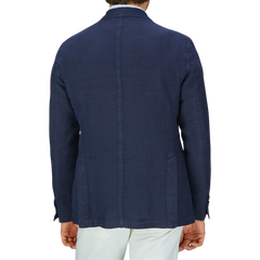 Rear view of a man wearing a tailored L.B.M. 1911 navy blue washed linen blazer and light-colored linen trousers.