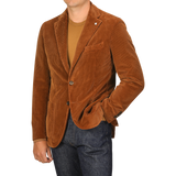 A person wearing an L.B.M. 1911 Cinnamon Brown Cotton Corduroy Blazer, a brown t-shirt, and dark blue jeans, with one hand in their pocket. The person’s face is not visible.