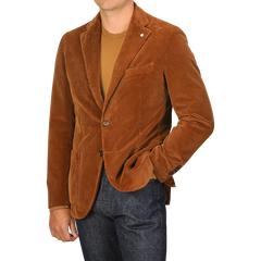 A person wearing an L.B.M. 1911 Cinnamon Brown Cotton Corduroy Blazer, a brown t-shirt, and dark blue jeans, with one hand in their pocket. The person’s face is not visible.