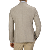 A man dressed in an Oatmel Beige Shetland Wool Cashmere Blazer by L.B.M. 1911, a light blue shirt, and khaki pants is seen from the back, with his right hand in his pocket.