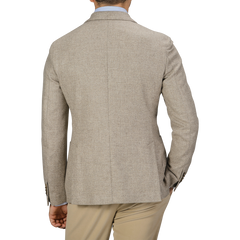 A man dressed in an Oatmel Beige Shetland Wool Cashmere Blazer by L.B.M. 1911, a light blue shirt, and khaki pants is seen from the back, with his right hand in his pocket.