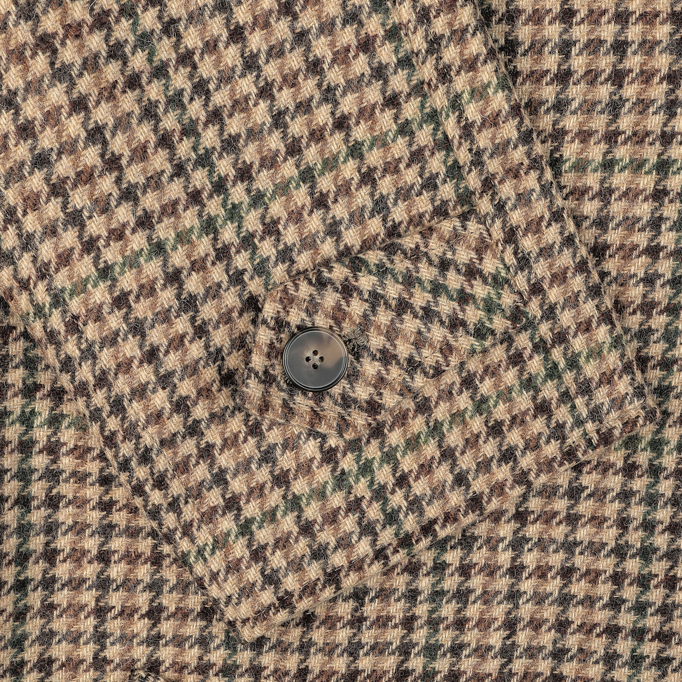 Close-up of a sleeve from the L'Impermeabile Beige Houndstooth Wool Tweed Reversible Coat, featuring a dark button fastened on the cuff.