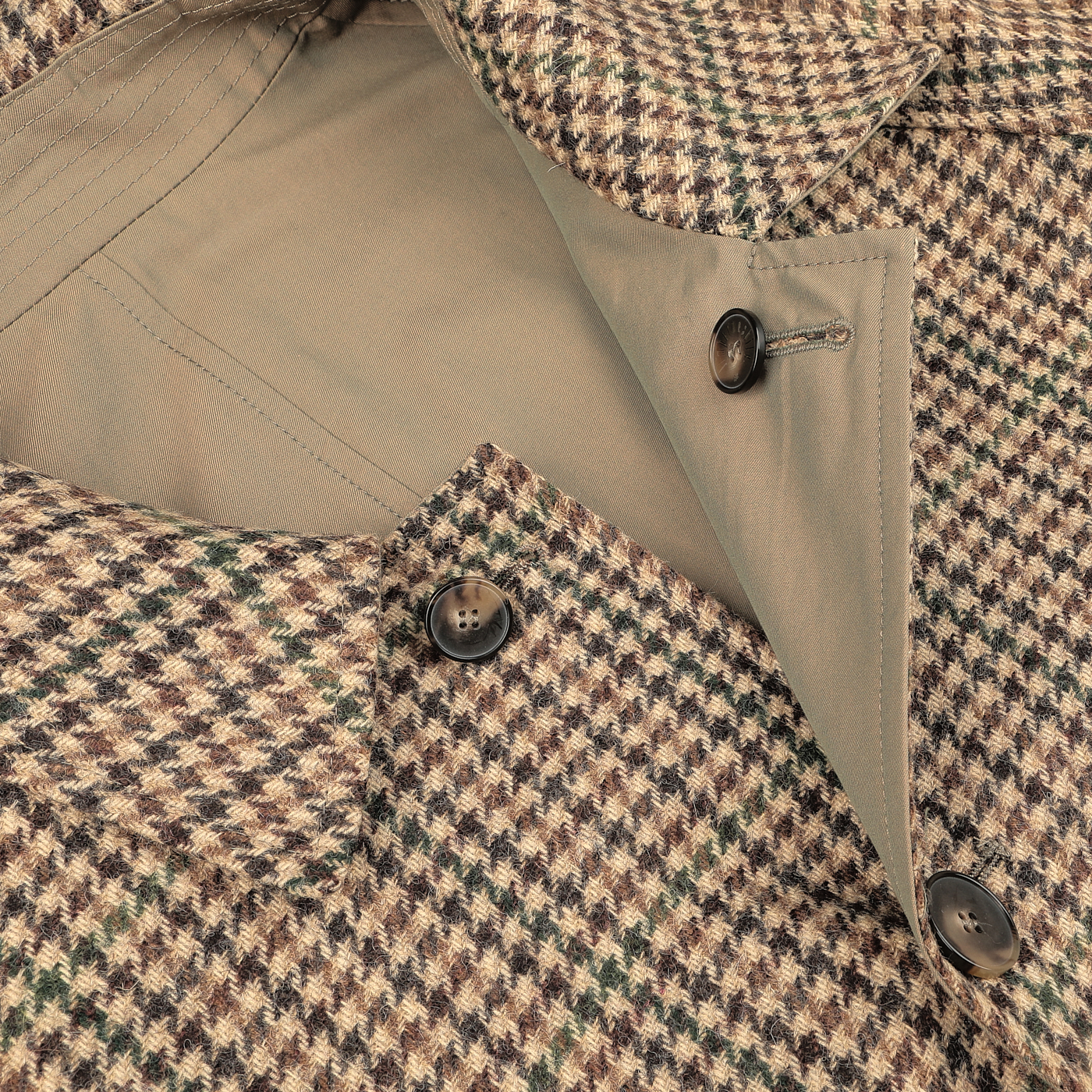 Close-up image of L'Impermeabile's Beige Houndstooth Wool Tweed Reversible Coat, highlighting its buttons, inner lining, and stitching details. The coat boasts a classic design with dark buttons and a beige interior lining.