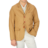 A man wearing a Camel Beige Waxed Linen College LL jacket by L'Impermeabile and white pants.