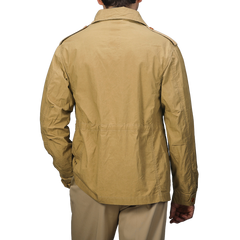 A person in a Khaki Beige Waxed Cotton Smith SFO Jacket by L'Impermeabile, highlighting exquisite Italian craftsmanship, stands with their back to the camera against a gray background.