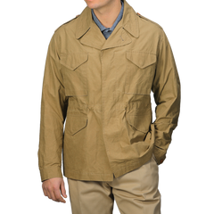 Someone wearing a Khaki Beige Waxed Cotton Smith SFO Jacket by L'Impermeabile, known for Italian craftsmanship and multiple pockets, is paired with a light blue shirt and khaki pants.