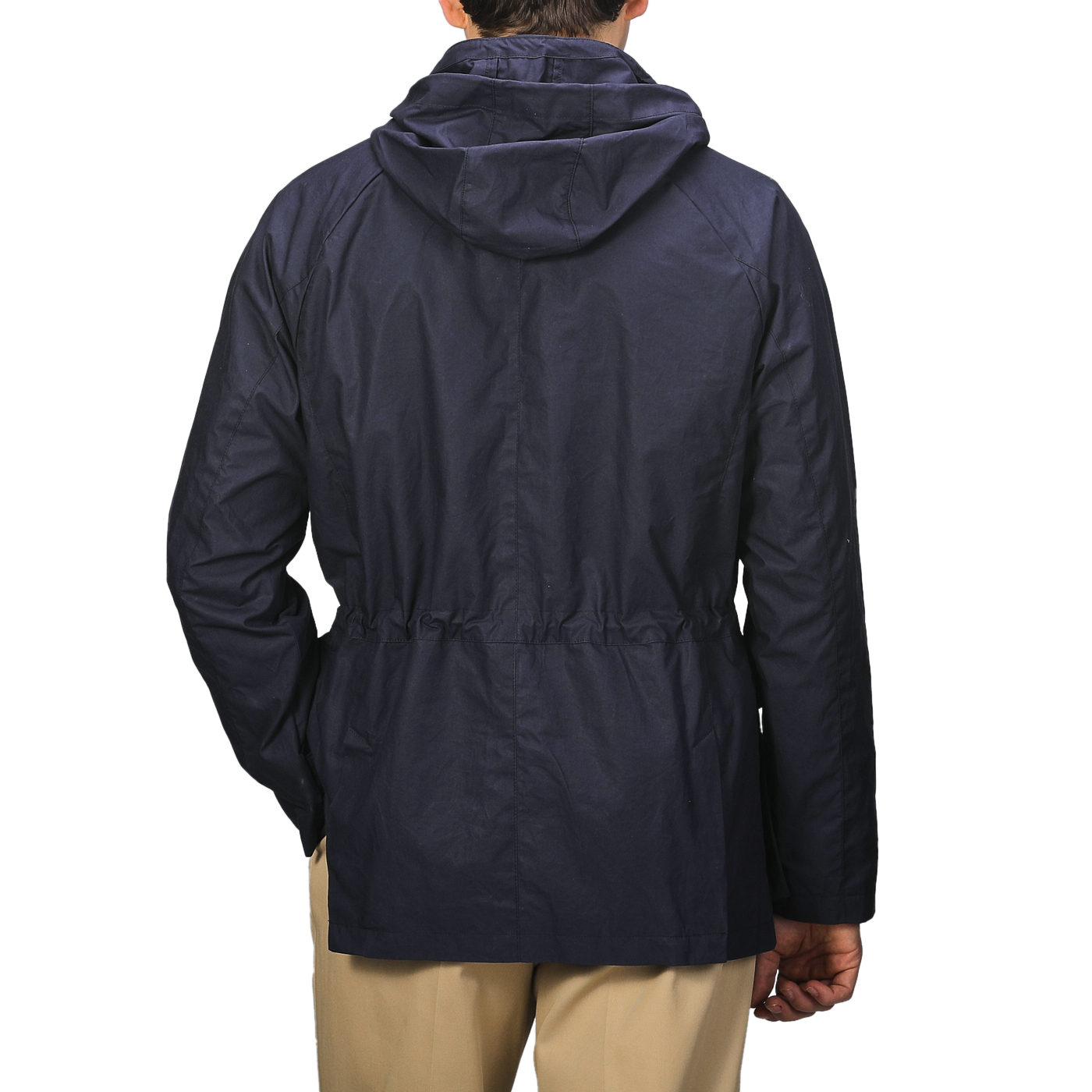 An individual is seen from behind against a plain background, wearing the L'Impermeabile Navy Blue Waxed Cotton Bob Short Parka and beige pants.