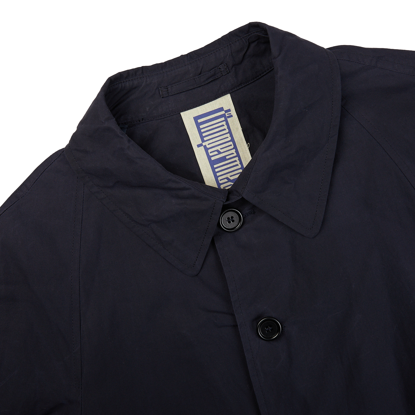 A close up of a L'Impermeabile navy blue waxed cotton Kamikaze trenchcoat on a white background.