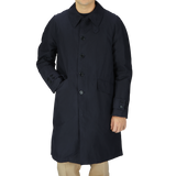 A young man wearing a Navy Blue Waxed Cotton Kamikaze trench coat from L'Impermeabile Italy.