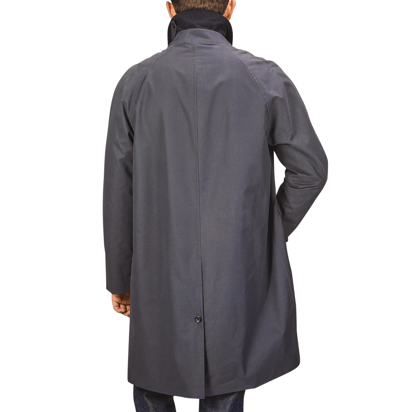 A person is standing with their back to the camera, wearing a knee-length Washed Blue Waxed Cotton Kamikaze Coat with a high collar and long sleeves from L'Impermeabile, made from wind and water-resistant waxed cotton.