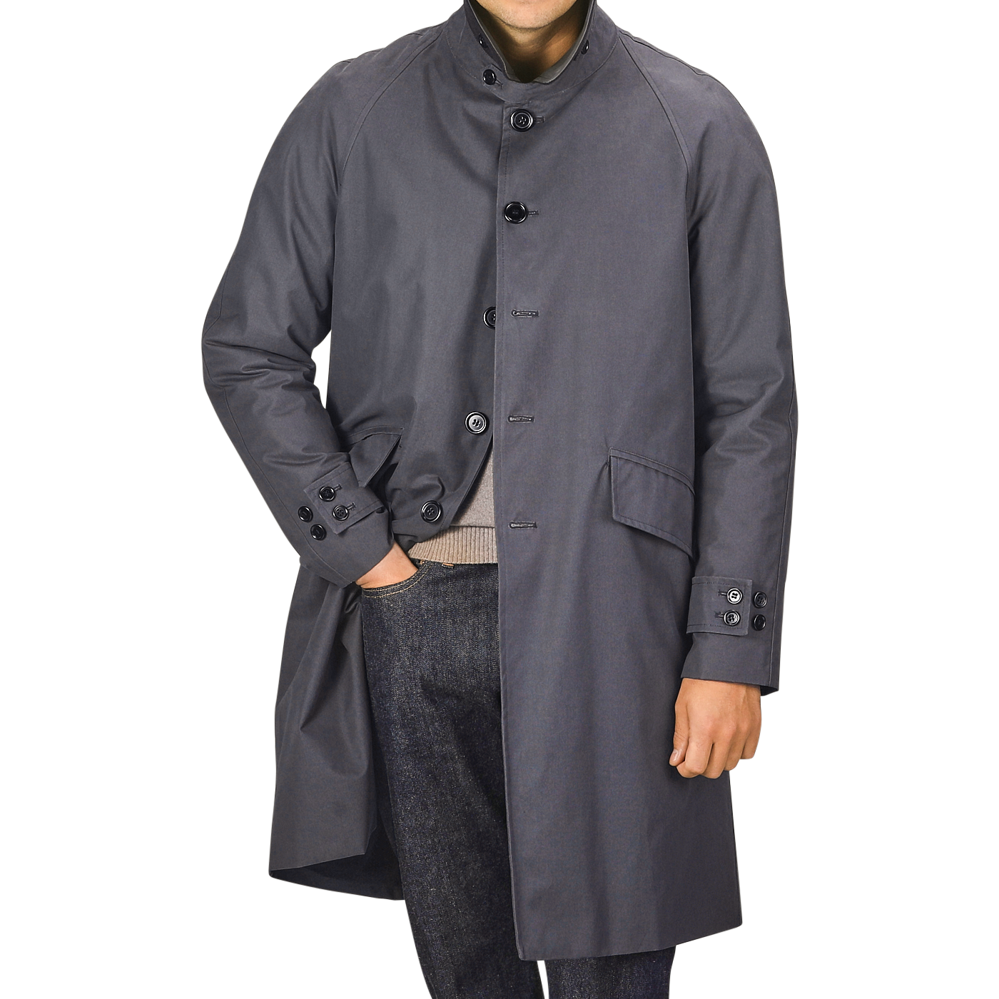 A person wearing a washed blue waxed cotton Kamikaze Coat by L'Impermeabile, one hand in their pants pocket. Their face is not visible.