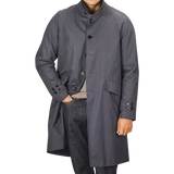 A person wearing a washed blue waxed cotton Kamikaze Coat by L'Impermeabile, one hand in their pants pocket. Their face is not visible.